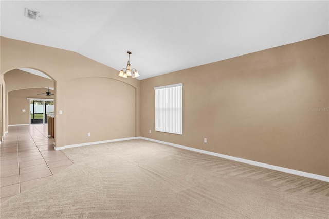 carpeted spare room with ceiling fan with notable chandelier and vaulted ceiling