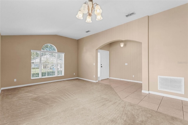 carpeted spare room with lofted ceiling and a chandelier