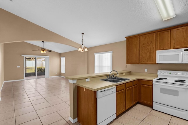 kitchen featuring light tile patterned floors, kitchen peninsula, sink, white appliances, and vaulted ceiling