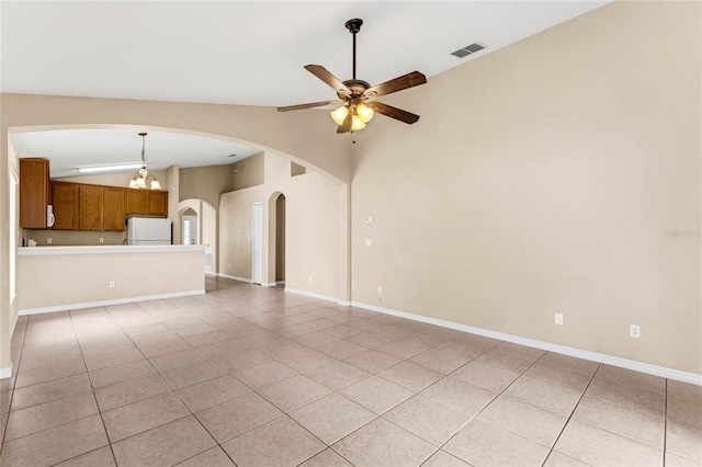 unfurnished living room featuring ceiling fan with notable chandelier, lofted ceiling, and light tile patterned flooring