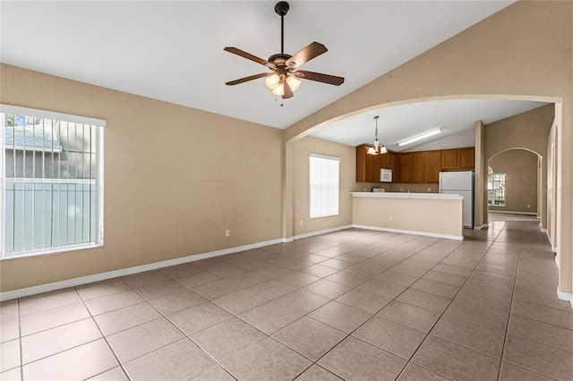 unfurnished living room featuring a wealth of natural light, vaulted ceiling, and light tile patterned floors