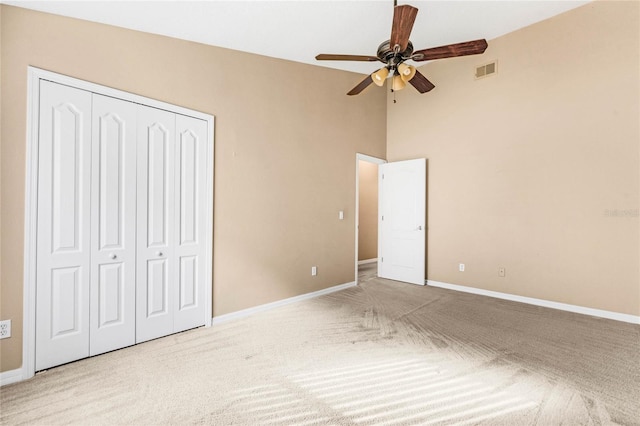 unfurnished bedroom featuring ceiling fan, light colored carpet, and a closet