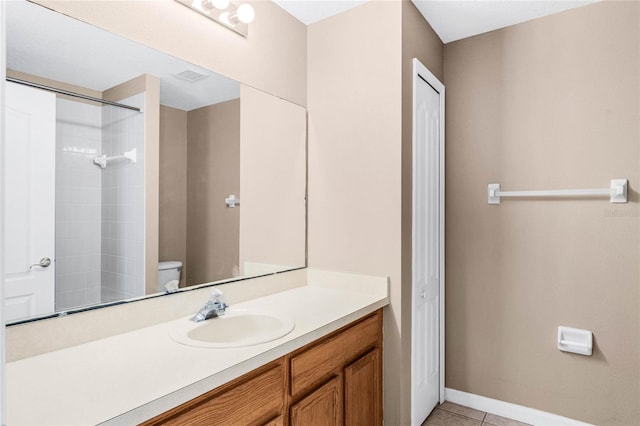 bathroom with vanity, tile patterned flooring, toilet, and tiled shower