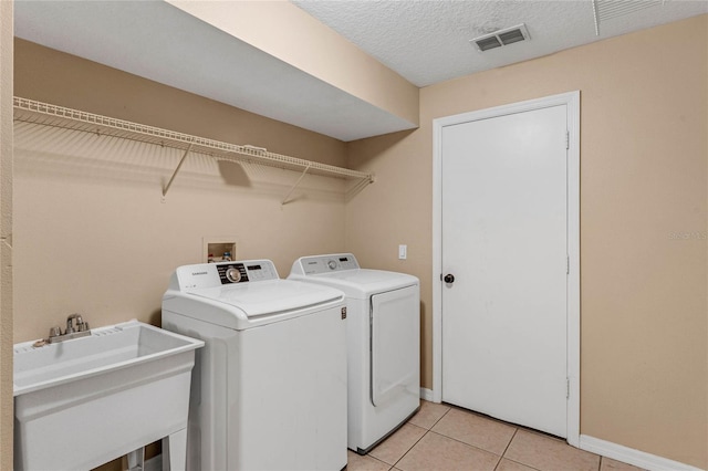 laundry area featuring light tile patterned floors, sink, and washer and dryer