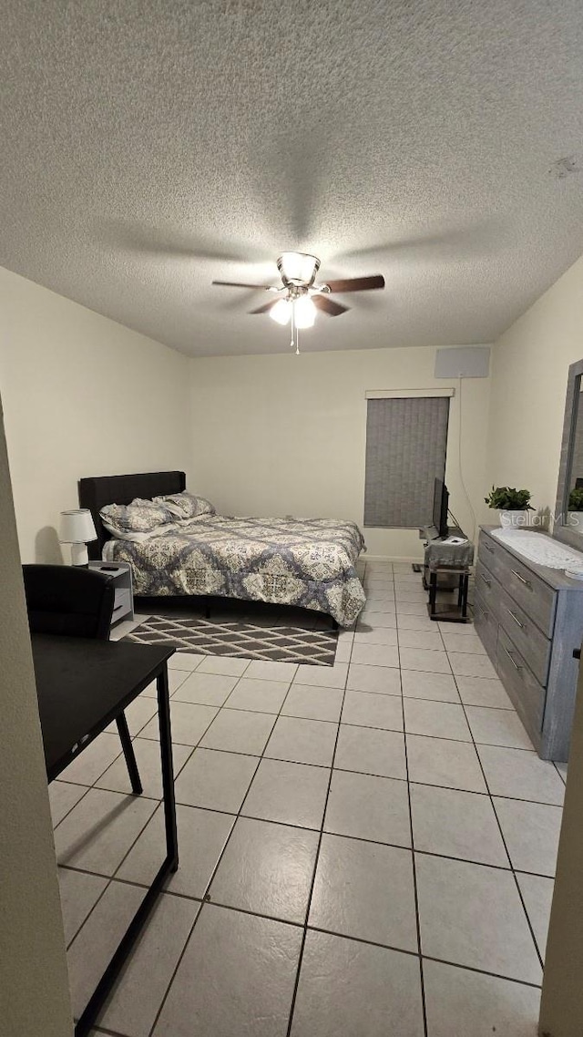 bedroom with a textured ceiling, light tile patterned floors, and ceiling fan