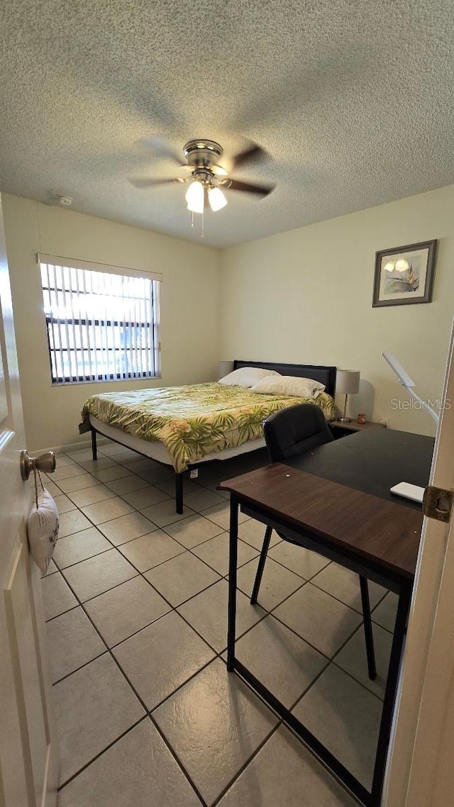 bedroom with ceiling fan, a textured ceiling, and light tile patterned floors