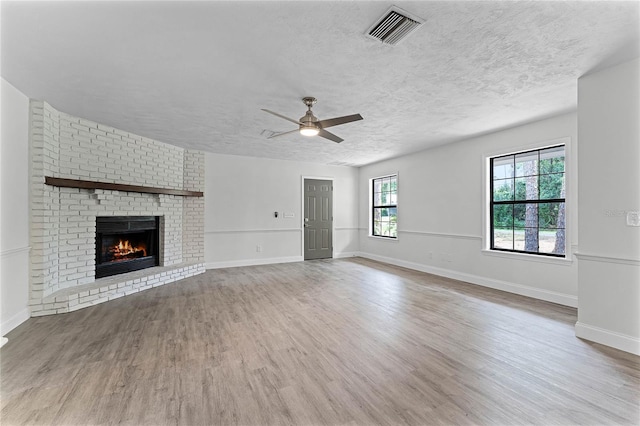 unfurnished living room featuring hardwood / wood-style flooring, a textured ceiling, and a wealth of natural light