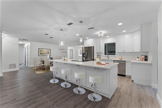 kitchen featuring appliances with stainless steel finishes, a breakfast bar, pendant lighting, white cabinets, and a center island