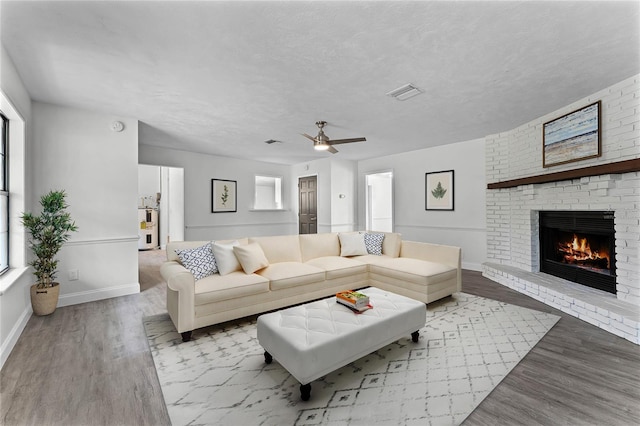 living room featuring a textured ceiling, a fireplace, and light hardwood / wood-style flooring