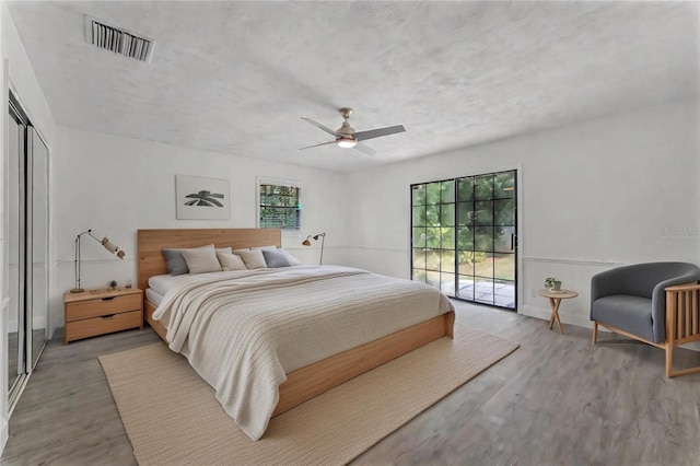 bedroom featuring access to exterior, hardwood / wood-style flooring, a closet, and ceiling fan