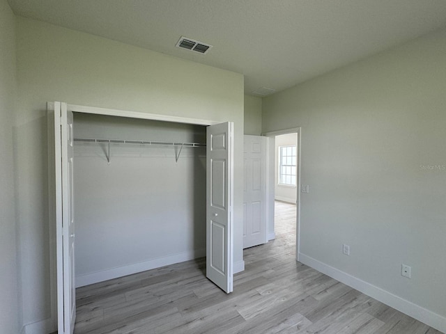 unfurnished bedroom featuring light hardwood / wood-style floors and a closet