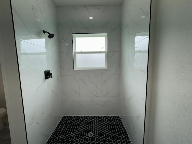 bathroom featuring tiled shower and toilet