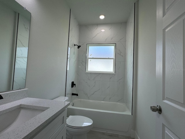 full bathroom featuring tiled shower / bath combo, vanity, and toilet