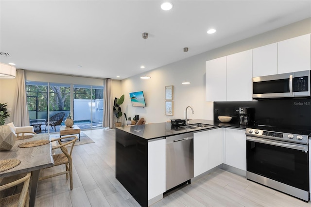 kitchen with kitchen peninsula, light hardwood / wood-style flooring, stainless steel appliances, and white cabinets