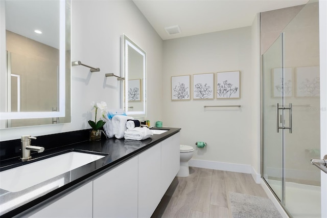 bathroom featuring walk in shower, vanity, toilet, and hardwood / wood-style flooring