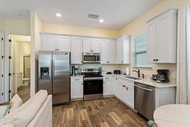 kitchen featuring stainless steel appliances, white cabinetry, dark wood-type flooring, and sink