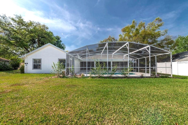 rear view of property with a fenced in pool, glass enclosure, and a lawn