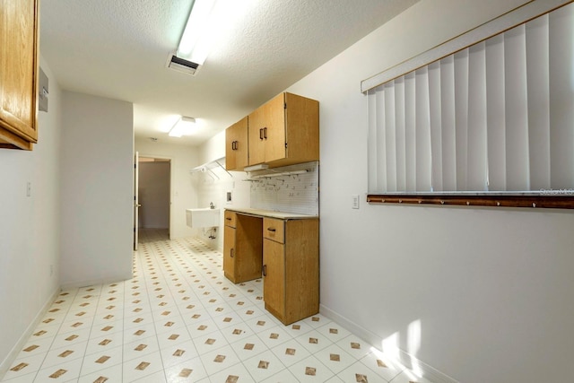 kitchen featuring a textured ceiling, tasteful backsplash, and sink