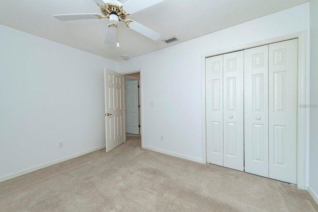 unfurnished bedroom featuring ceiling fan, light colored carpet, and a closet