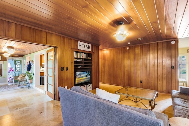 living room featuring wood walls, ceiling fan, and wooden ceiling