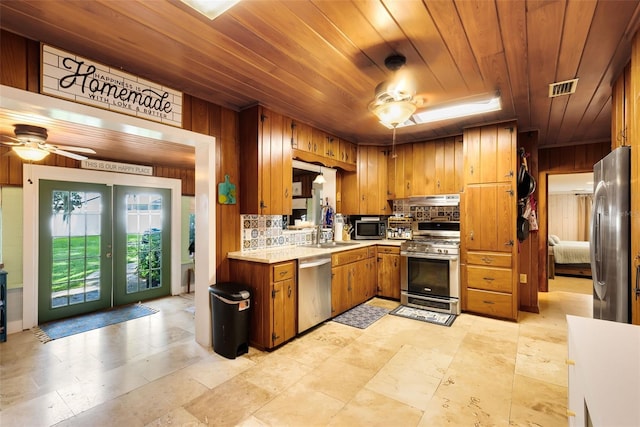 kitchen with tasteful backsplash, french doors, wood ceiling, stainless steel appliances, and wooden walls