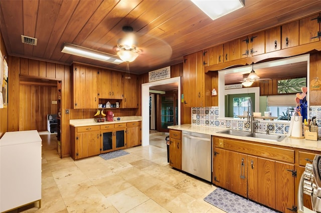 kitchen with tasteful backsplash, appliances with stainless steel finishes, sink, pendant lighting, and wooden walls