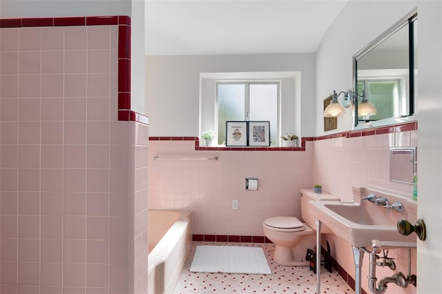 bathroom with toilet, a tub, tile walls, and tile patterned flooring