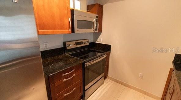 kitchen featuring dark stone countertops and stainless steel appliances