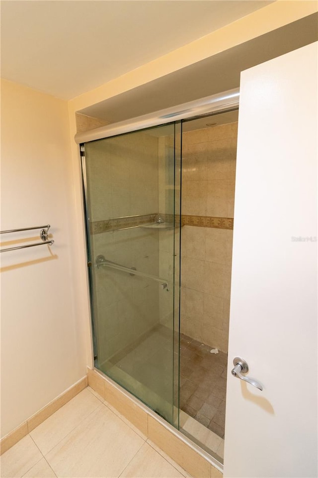 bathroom with a shower with shower door and tile patterned flooring