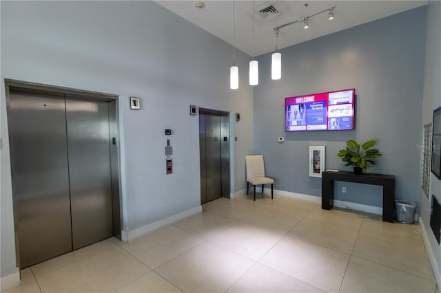 hall with light tile patterned flooring, elevator, and high vaulted ceiling