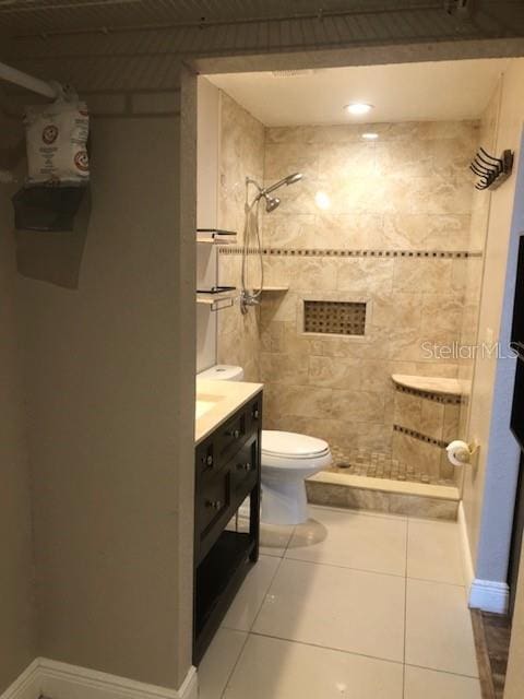 bathroom featuring toilet, vanity, tile patterned floors, and tiled shower