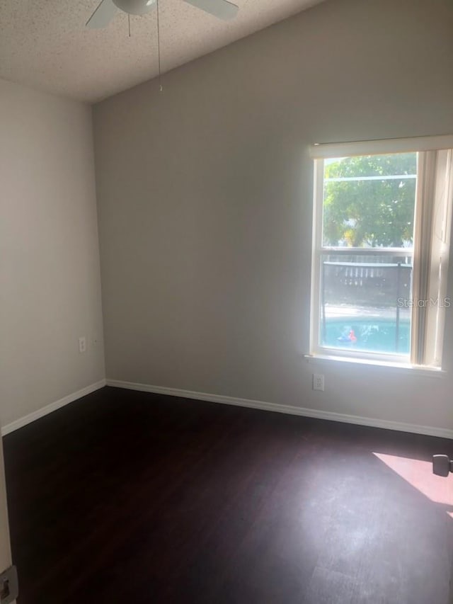 empty room with a textured ceiling, ceiling fan, and dark hardwood / wood-style flooring