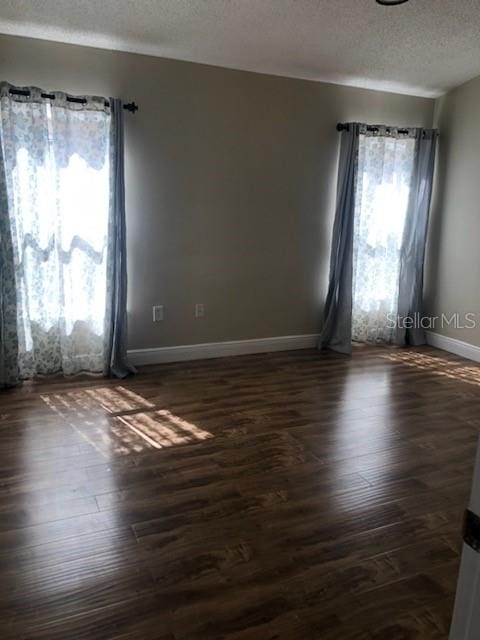 unfurnished room with dark hardwood / wood-style floors and a textured ceiling