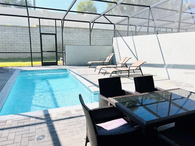 view of swimming pool featuring a patio and glass enclosure