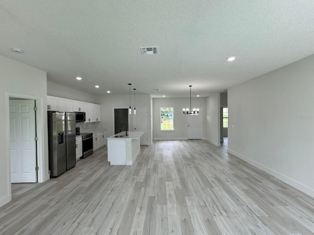 kitchen featuring pendant lighting, light hardwood / wood-style flooring, a center island with sink, white cabinetry, and stainless steel appliances