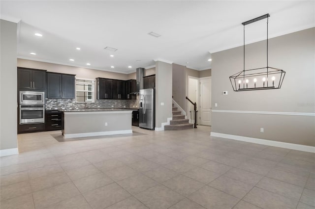 kitchen featuring pendant lighting, appliances with stainless steel finishes, crown molding, and a kitchen island