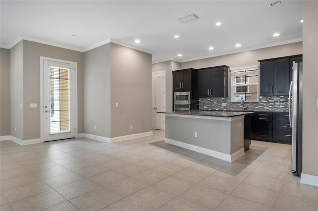 kitchen with dark stone countertops, a kitchen island, crown molding, and stainless steel appliances