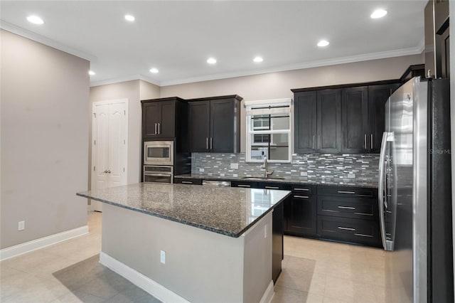 kitchen featuring a kitchen island, dark stone countertops, backsplash, appliances with stainless steel finishes, and ornamental molding