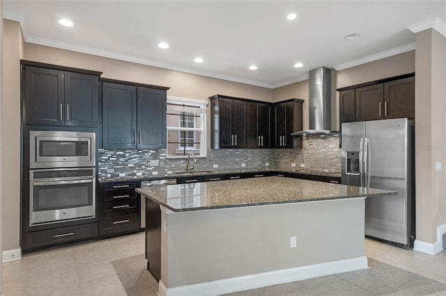 kitchen featuring appliances with stainless steel finishes, wall chimney exhaust hood, dark stone countertops, and a center island