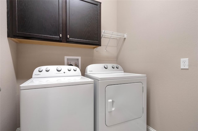 clothes washing area featuring washing machine and dryer and cabinets