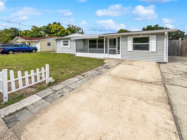 ranch-style home with a front yard, a sunroom, and a patio area