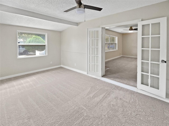 empty room featuring french doors, a textured ceiling, and carpet