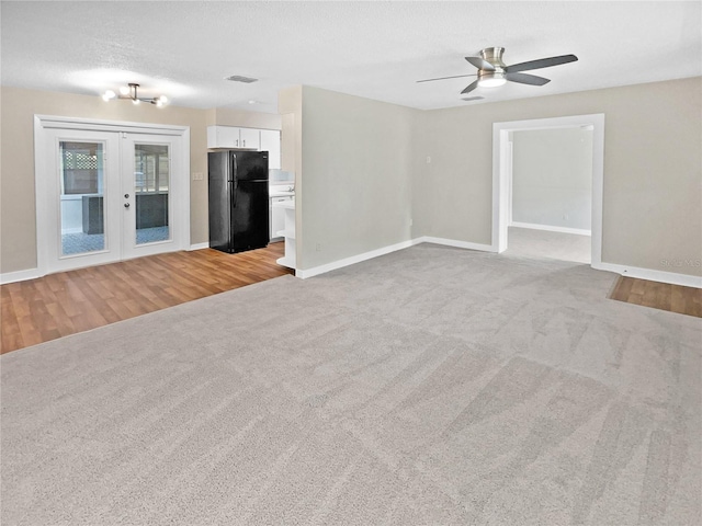 unfurnished living room with a textured ceiling, light hardwood / wood-style floors, ceiling fan, and french doors