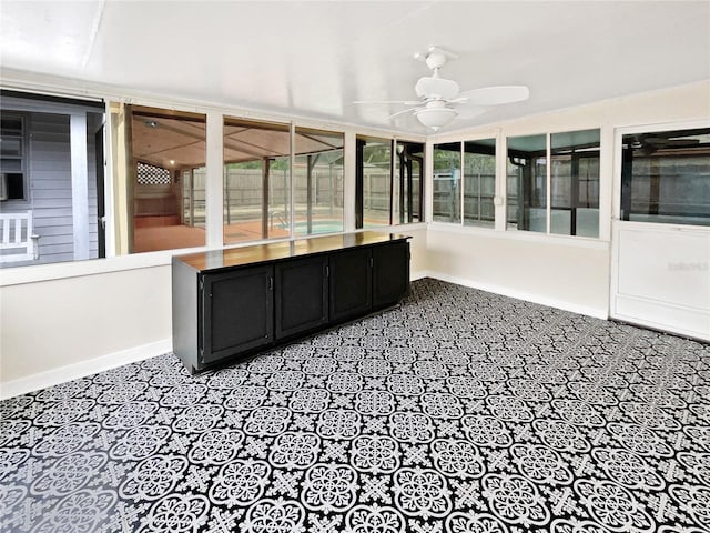 unfurnished sunroom with ceiling fan