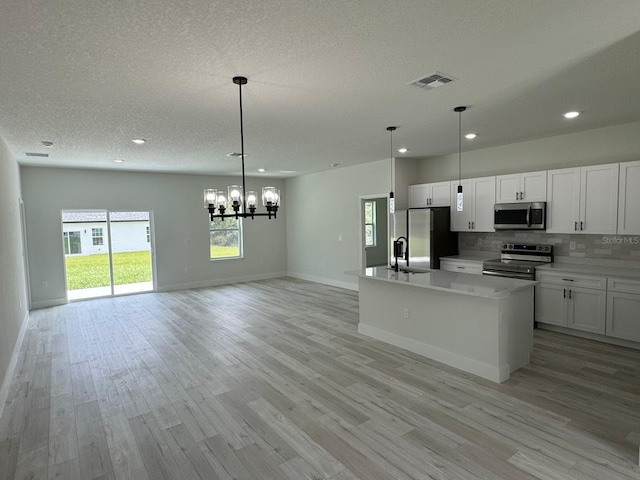 kitchen featuring appliances with stainless steel finishes, a center island with sink, light hardwood / wood-style floors, and white cabinets