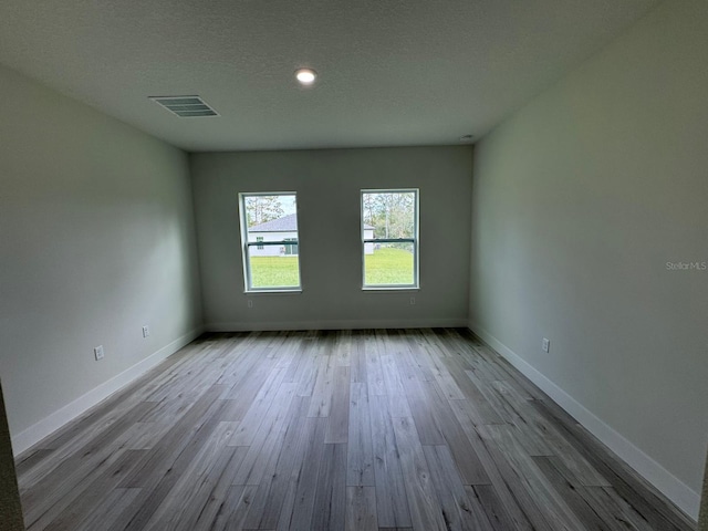 spare room featuring a textured ceiling and light hardwood / wood-style floors