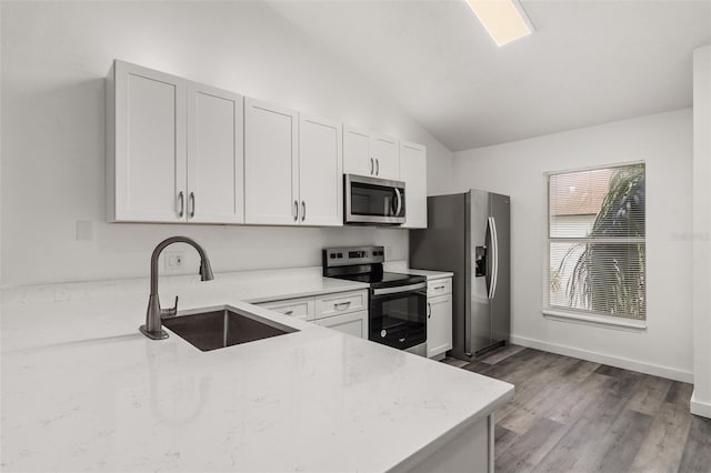 kitchen with lofted ceiling, sink, stainless steel appliances, light stone counters, and white cabinets