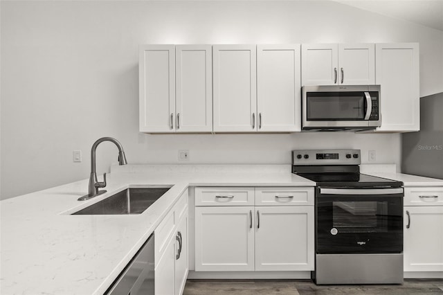 kitchen with white cabinetry, appliances with stainless steel finishes, sink, and light stone counters