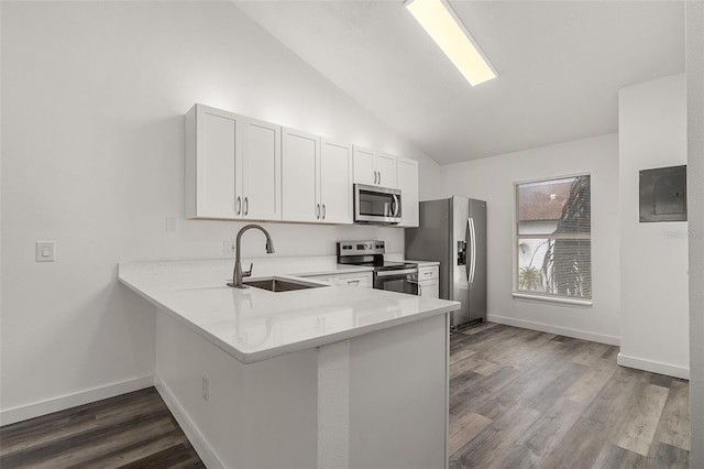 kitchen with vaulted ceiling, appliances with stainless steel finishes, sink, white cabinets, and kitchen peninsula