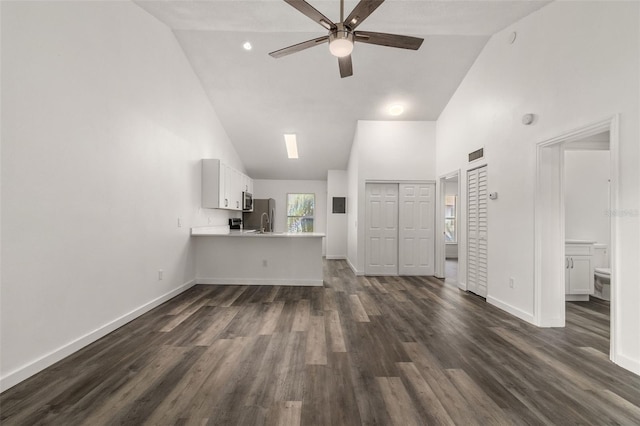 unfurnished living room with ceiling fan, dark hardwood / wood-style floors, and high vaulted ceiling